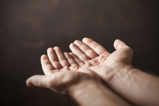 hands begging on a brown background