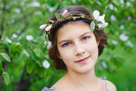 Portrait of adorable girl in blooming apple tree garden on spring day