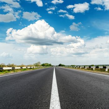 asphalt road with white line and blue sky with clouds over it
