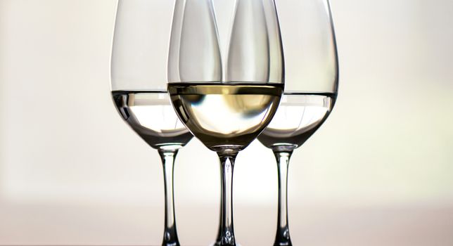 Four glasses of white wine, arranged symmetrically, focus on the middle one