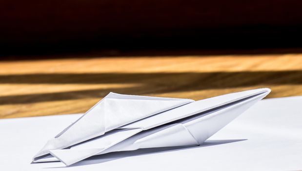 A nice origami speedboat over a sheet of paper and wood background