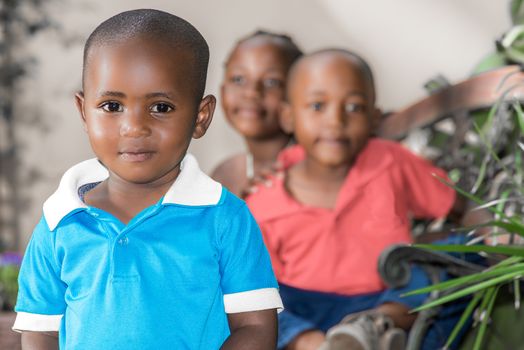 Little boy with his older brother and sister, who are twins, sitting behind him.