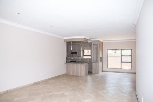 A vacant living room of a newly build home with the kitchen in the background.