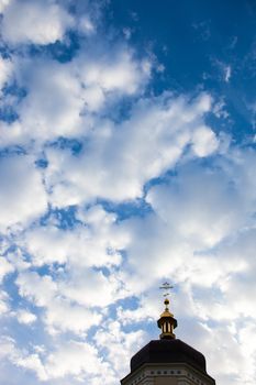 The cross of the orthodox Christian church against the cloudy sky background.