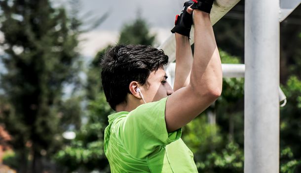 Young man doing pull-up on horizontal bar