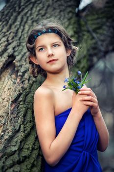 Adorable girl in forest with primroses flowers on spring day