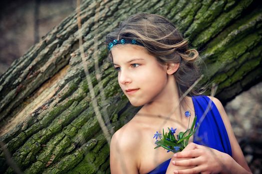 Adorable girl in forest with primroses flowers on spring day