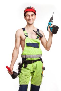 Young handsome workman holding a plunger and a electric screwdriver in light green uniform. Isolated over white background