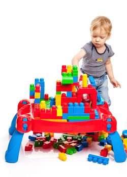 Toddler boy playing with building blocks on white background