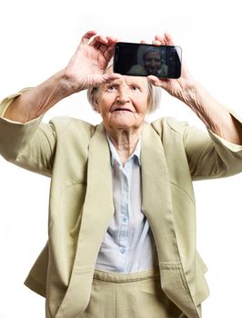 Happy elderly woman using touch screen mobile for taking selfie