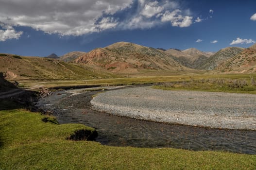 Scenic river in mountainous grassy landscape in Kyrgyzstan