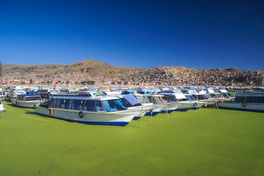 Boats on green water in harbor in Islas Flotantes de los Uros in Peru, South America