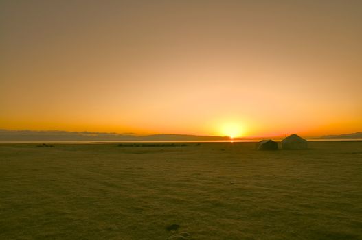 Scenic sunrise over traditional yurt of nomadic tribe on green grasslands in Kyrgyzstan