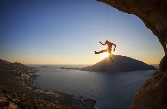 Male rock climber falling of a cliff while lead climbing at sunset