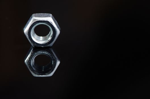 Metal female screws with reflection on black background.