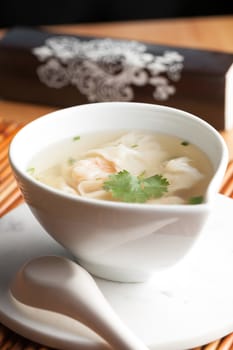 Thai shrimp wonton soup bowl close up with spoon.