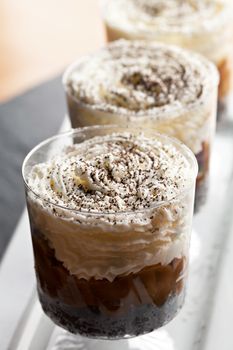 Banana caramel parfait desserts with fresh whipped cream and chocolate cookie crumbles. Shallow depth of field.