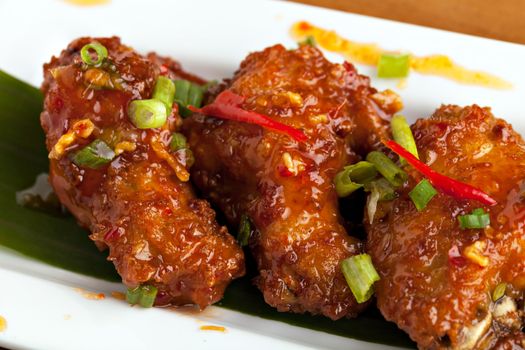 Thai style spicy chicken wings appetizer on a contemporary white plate.