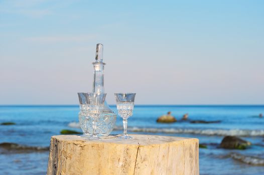 Crystal glasses and decanter on the stump at the sea