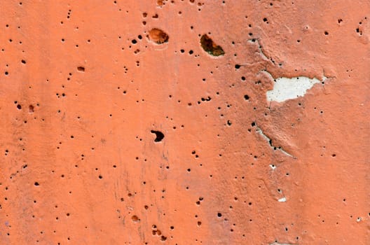 Texture of orange paint concrete surface with several holes.