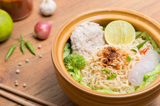 Hot and spicy noodle with pork and vegetables on the wood background