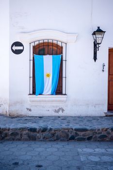 Argentina's famous blue, white and yellow flag hangs from the window of a Partriotic Argentinian persons house in South America.