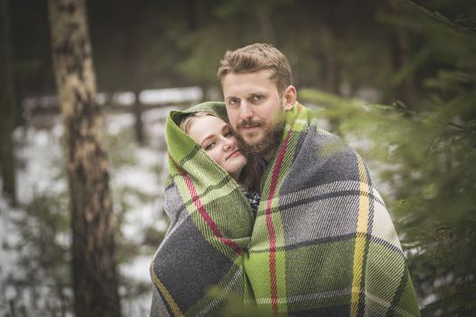 Lovers are trying to warm up in a wool plaid in woods