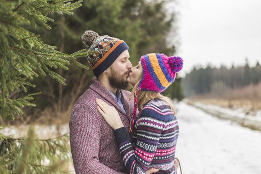 Christmas love couple walks in the wood in colorfull clothes