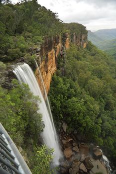Views of Fitzroy Falls from the grated balcony lookout at the top of the escarpment with a downward perspective capturing the first of the spectacular falls iover sheer vertical cliffs nto the eucalypt forests of the valleys below.  Morton National Park.