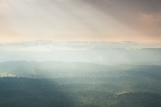 Sunlight shines through the clouds into the mountains and forests. Mist-covered mountains and trees.