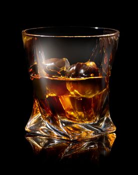 Glass of whiskey with ice on black background