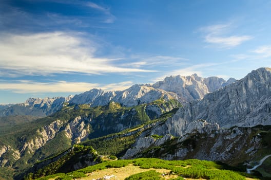 Aerial landscape view of summer Alps sunlight high mountain peaks with green valley and deep blue sky