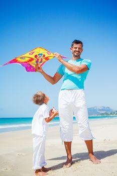 Summer vacation - Cute boy with his mother flying kite beach outdoor.