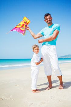 Summer vacation - Cute boy with his mother flying kite beach outdoor.