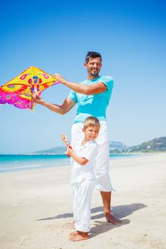 Summer vacation - Cute boy with his mother flying kite beach outdoor.