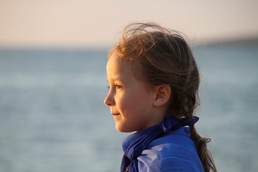 Girl by the sea in the profile face lit by the setting sun, happiness and joy
