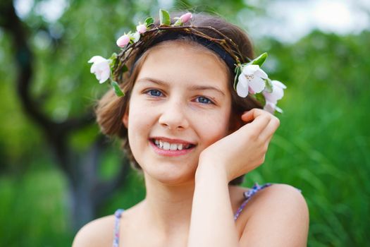 Portrait of adorable girl in blooming apple tree garden on spring day