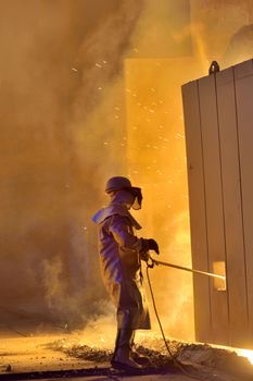 A steel worker takes a sample from oven