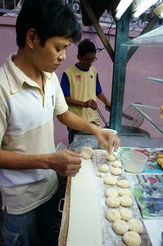 HO CHI MINH CITY, VIET NAM- DEC 17: Vietnamese food at Sai gon street, fried dumplings is popular street food, fast food, family of vendor make dish on pavement, Saigon, Vietnam, Dec 17, 2014