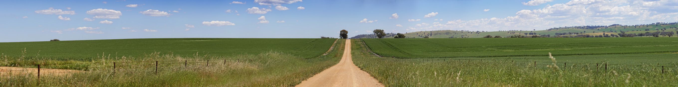 Miles of hilly dirt road carves up the fields of farmland in country NSW Australia