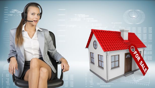 Businesswoman in headset sitting on office chair, looking at camera, speaking. Model house with tag for sale beside. Hi-tech graphs with various data as backdrop