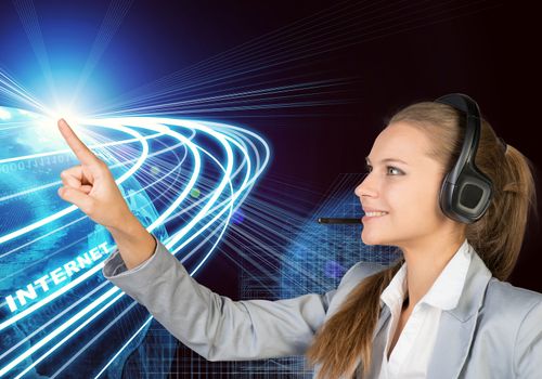 Businesswoman in headset touching spot of light with rays around, smiling. Beside is Globe surrounded by light streams of communication. Wire-frame building as backdrop