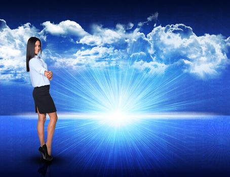 Businesswoman standing against digitally generated spacy blue landscape with rising sun and cloudy sky, looking at camera