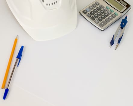 Hard hat, pen, pencil, calculator and compasses on white surface