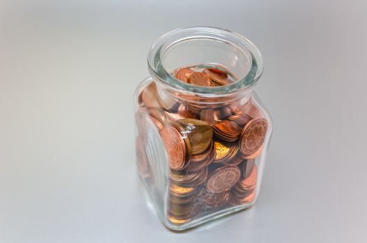 Detached glass filled with various Euro cent coins.