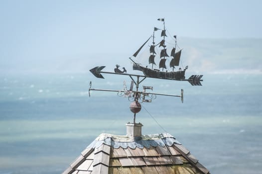 metal weather vane over a hazy coastline