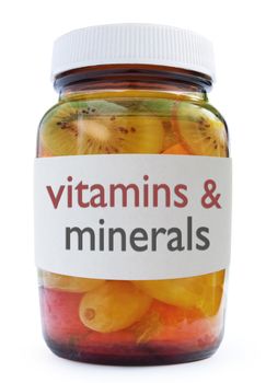 Vitamins and minerals medicine bottle packed with fruit over a white background