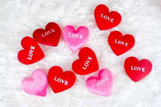 Decorated gifts with a heart shapes and text "love" embeded on, placed on feather background