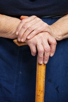 Closeup of senior woman's hands on wooden walking stick