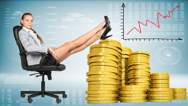 Businesswoman sitting on office chair with her feet up on piles of golden coins. Graph showing growth beside. Hi-tech charts with various data as backdrop